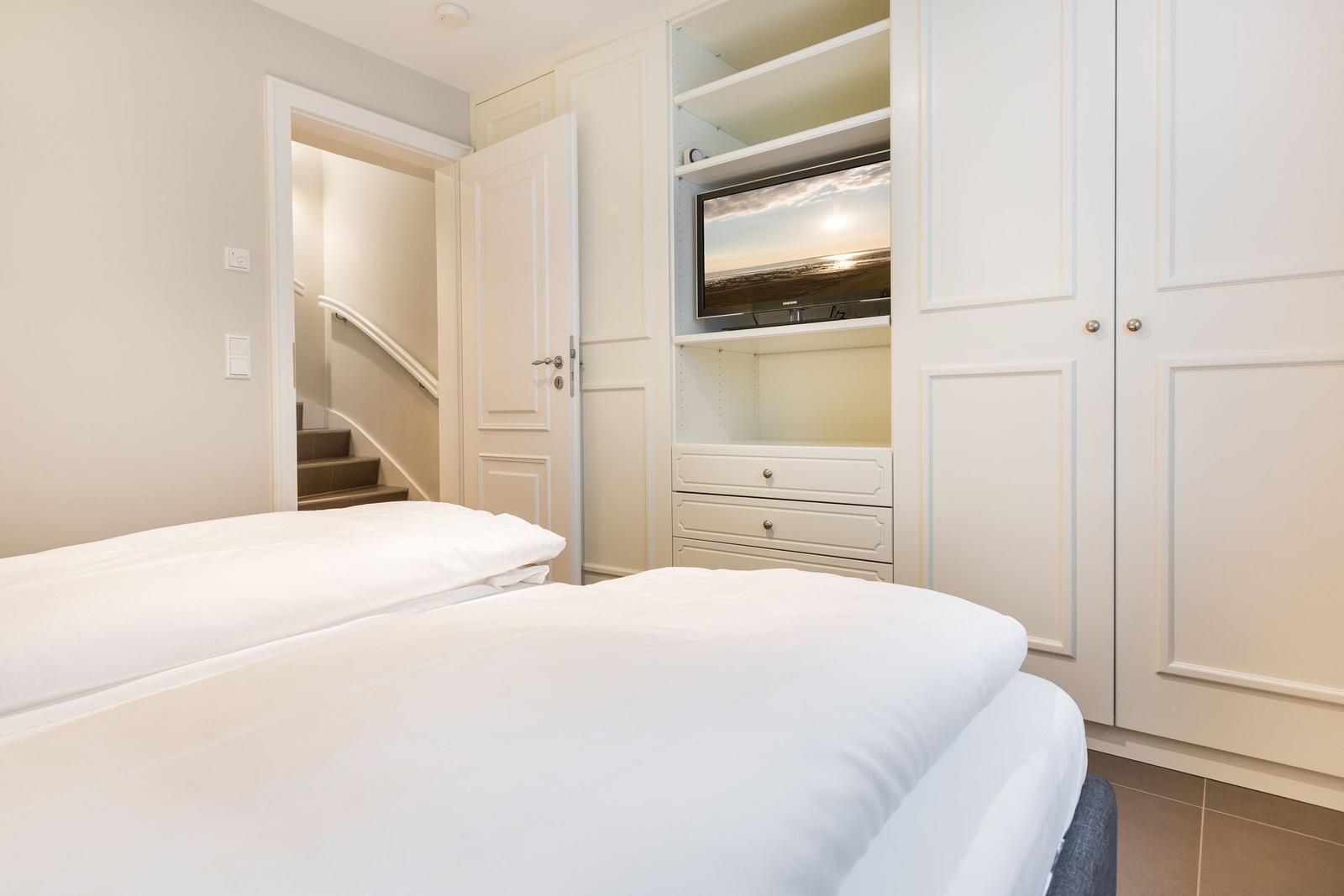 Schlafzimmer mit Bett, Kleiderschrank und TV in Wandnische