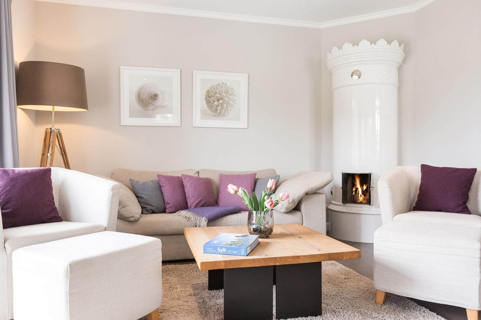 Wohnzimmer mit Sofa, Sesseln, Kamin und Tisch mit Blumen.