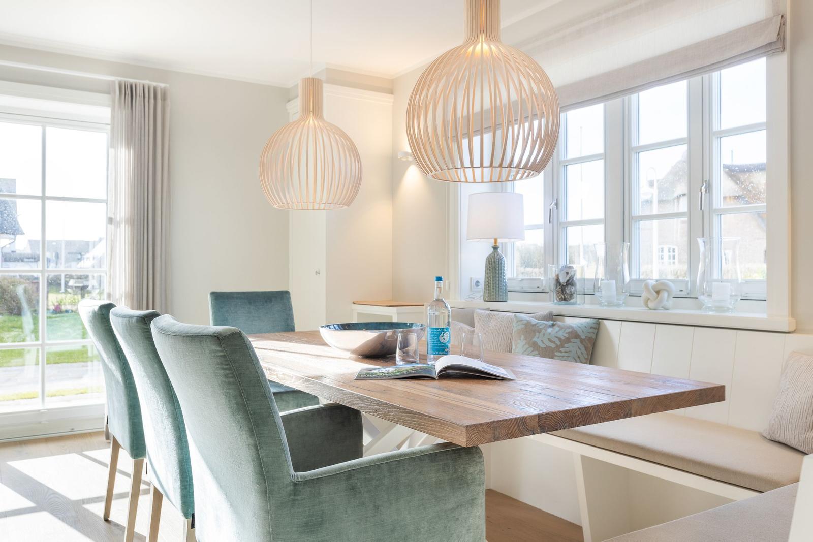 Esszimmer mit Holztisch, Sitzbank und zwei hängenden Lampen.