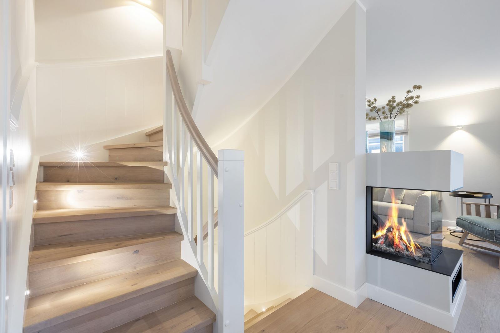 Holzgetreppe mit weißem Geländer und Kamin im Wohnbereich.