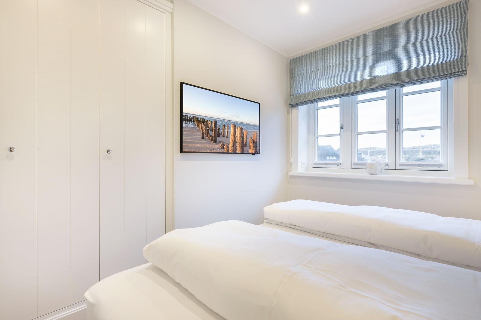 Schlafzimmer mit weißem Bett, Fenster und Wandbild.