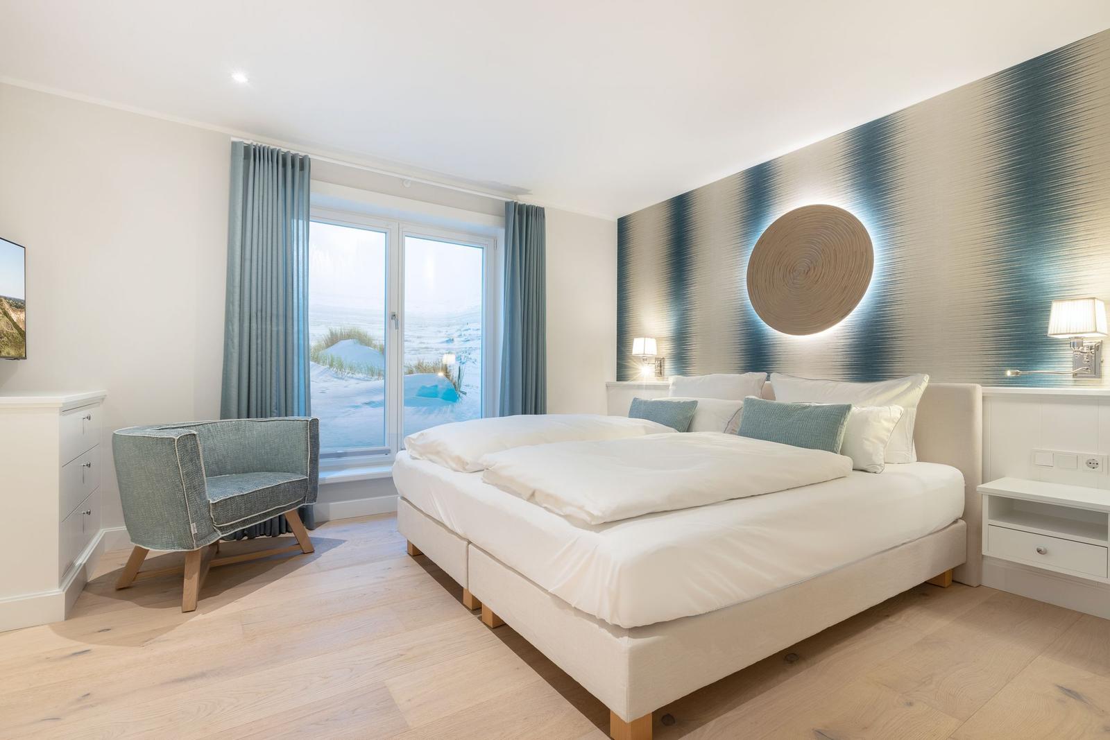 Schlafzimmer mit großem Bett und Fensterblick auf Schneelandschaft.