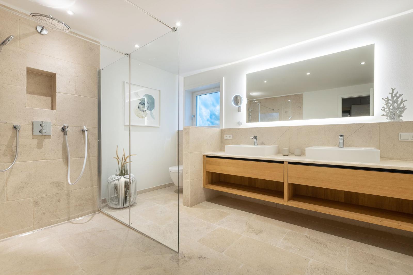 Moderne Dusche mit Glaswand, zwei Waschbecken und Spiegelschrank.