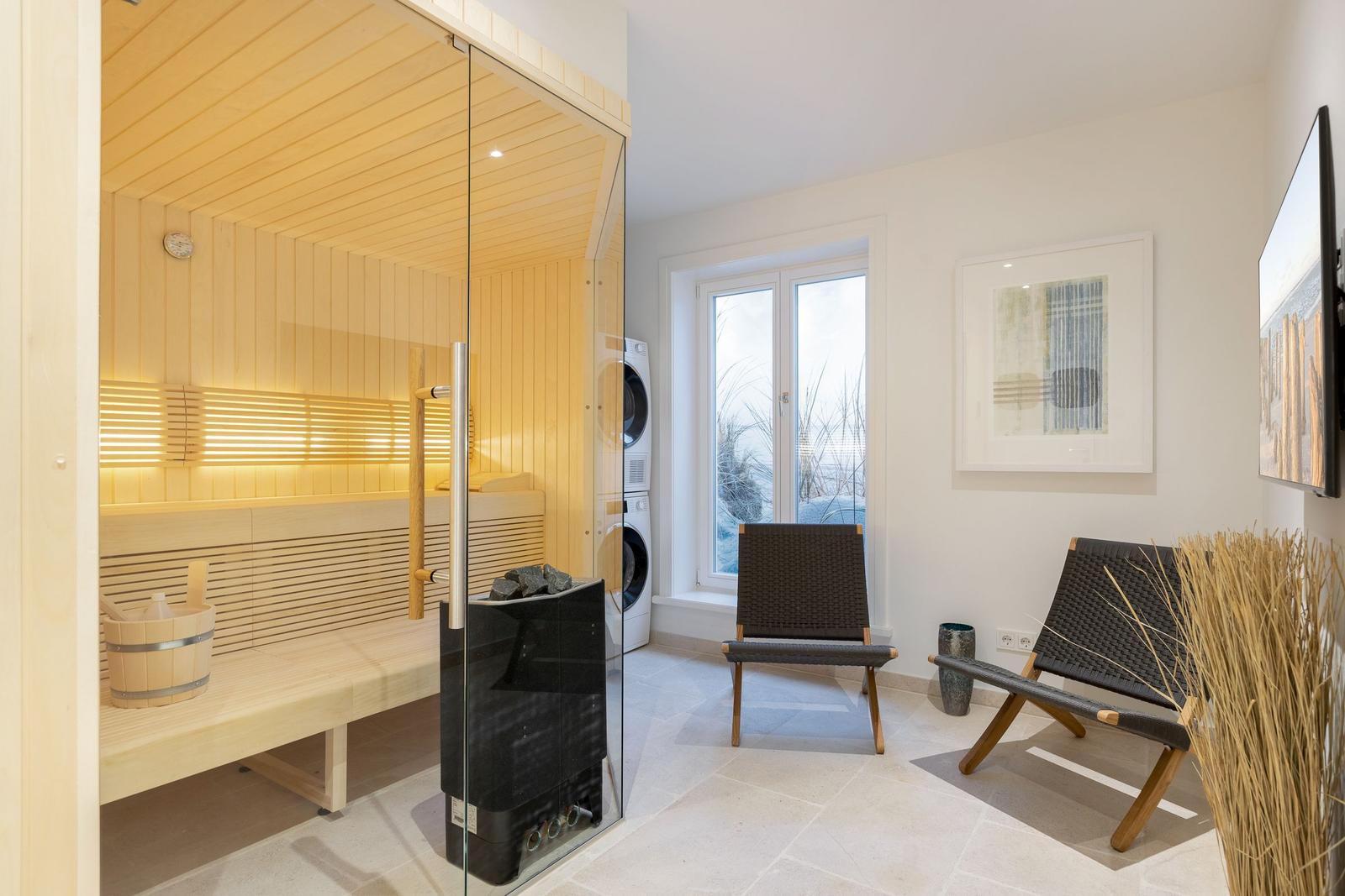 Sauna mit Glaswand, zwei Stühle und Fenster mit Blick draußen.