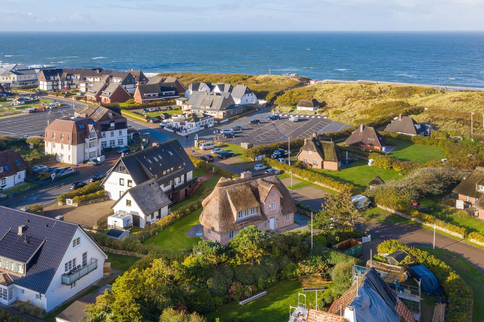 Dorf mit Strand, Häusern und grünen Wiesen an der Küste