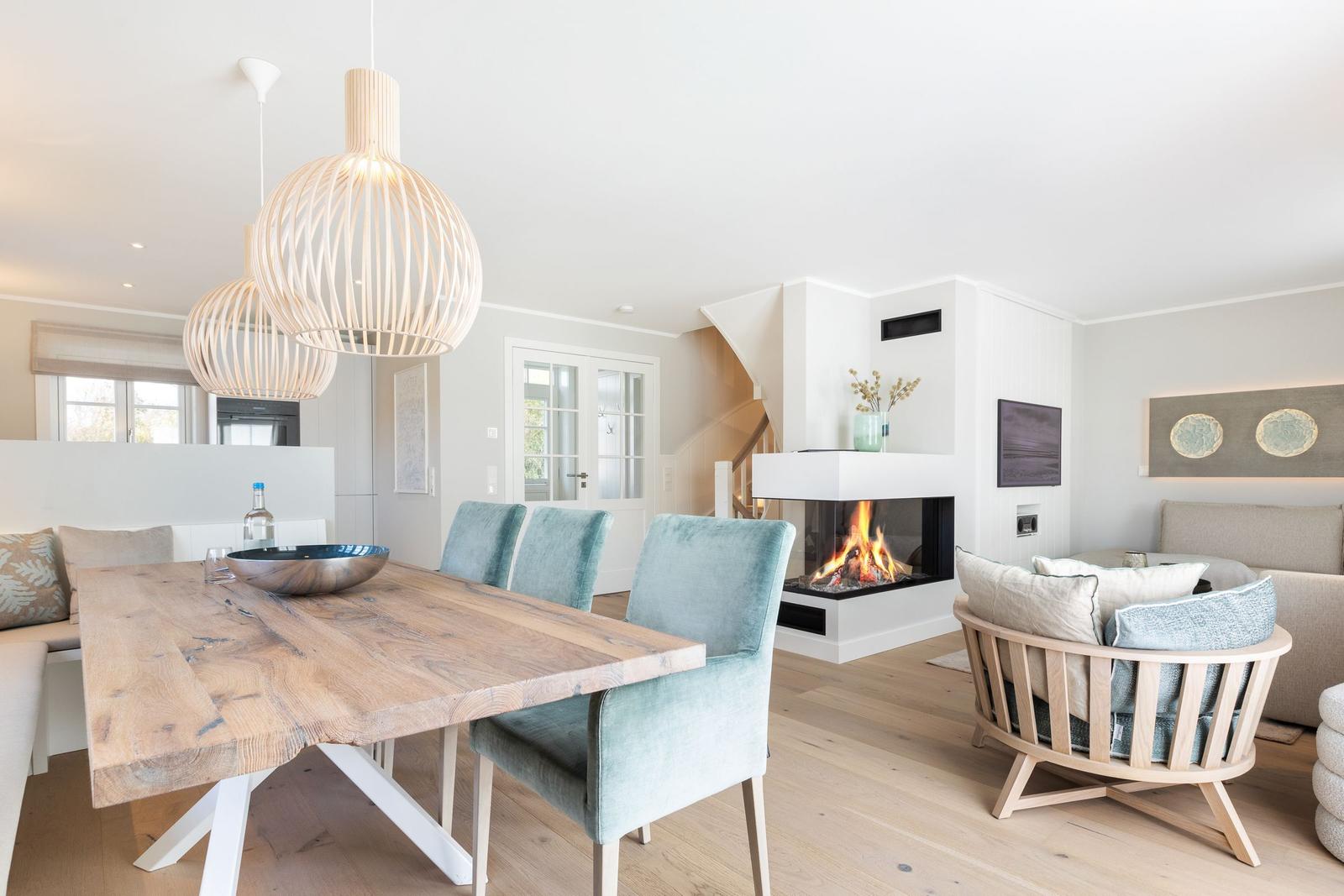 Essbereich mit Holztisch und Stühlen, Kamin und Sitzgelegenheiten im Wohnbereich.
