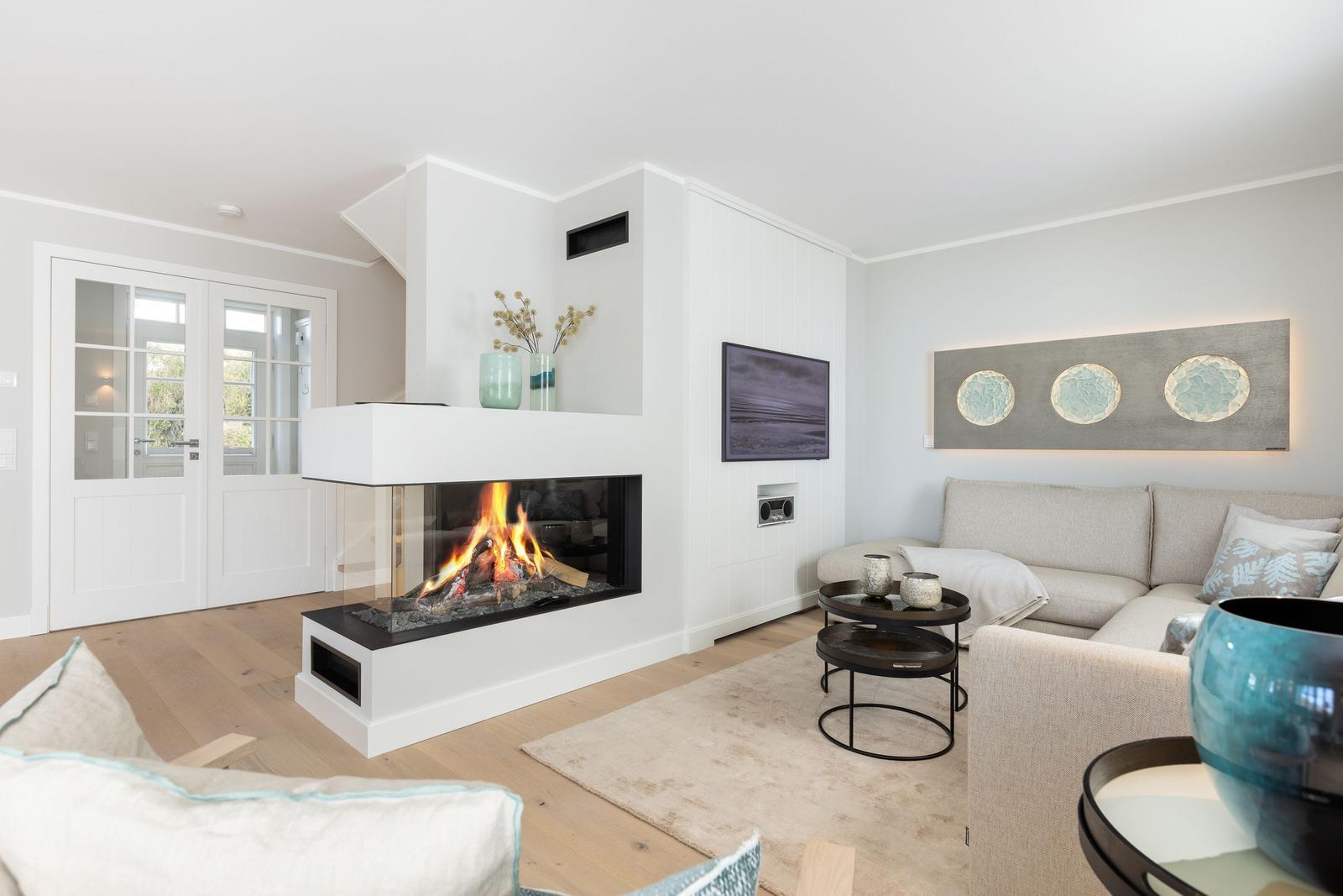 Wohnzimmer mit Kamin, Sofa und Fernseher an der Wand.
