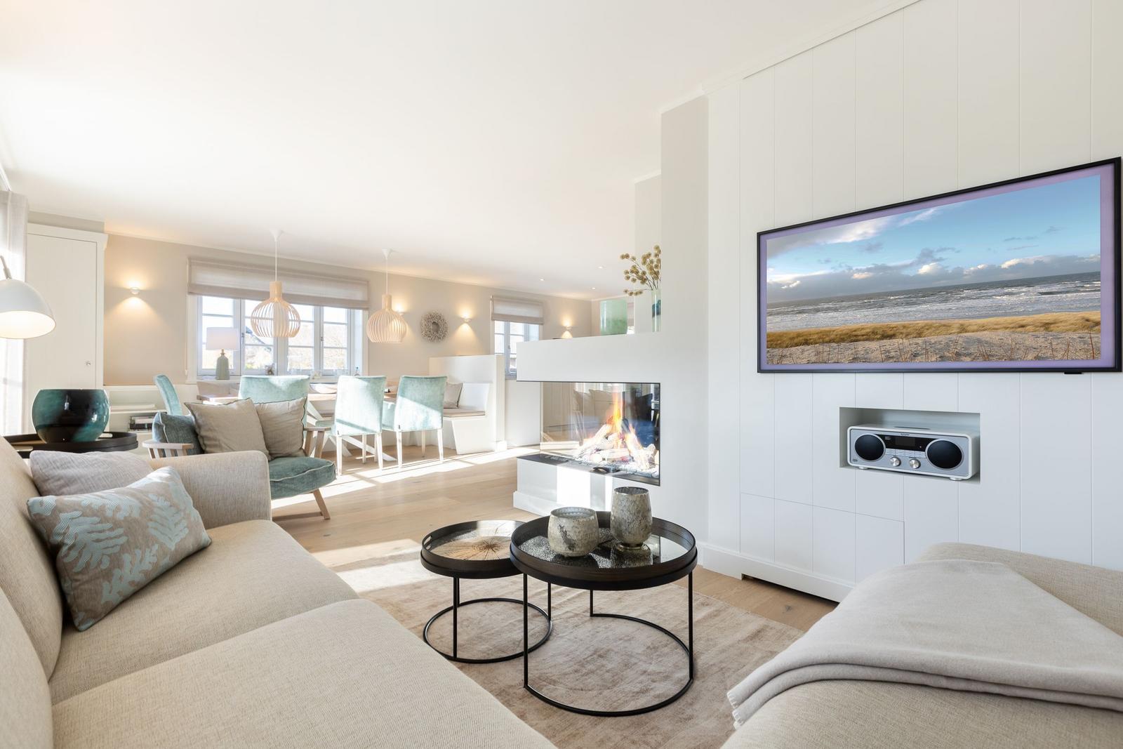 Wohnzimmer mit Kamin, Sofa und Fernseher an weißer Wand.