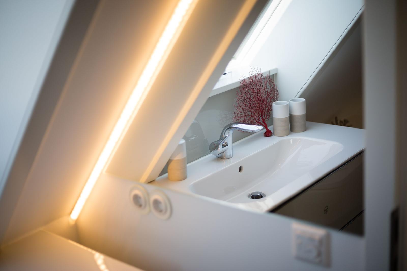 Waschbecken mit Spiegel und roter Dekoration unter Dachschrägen