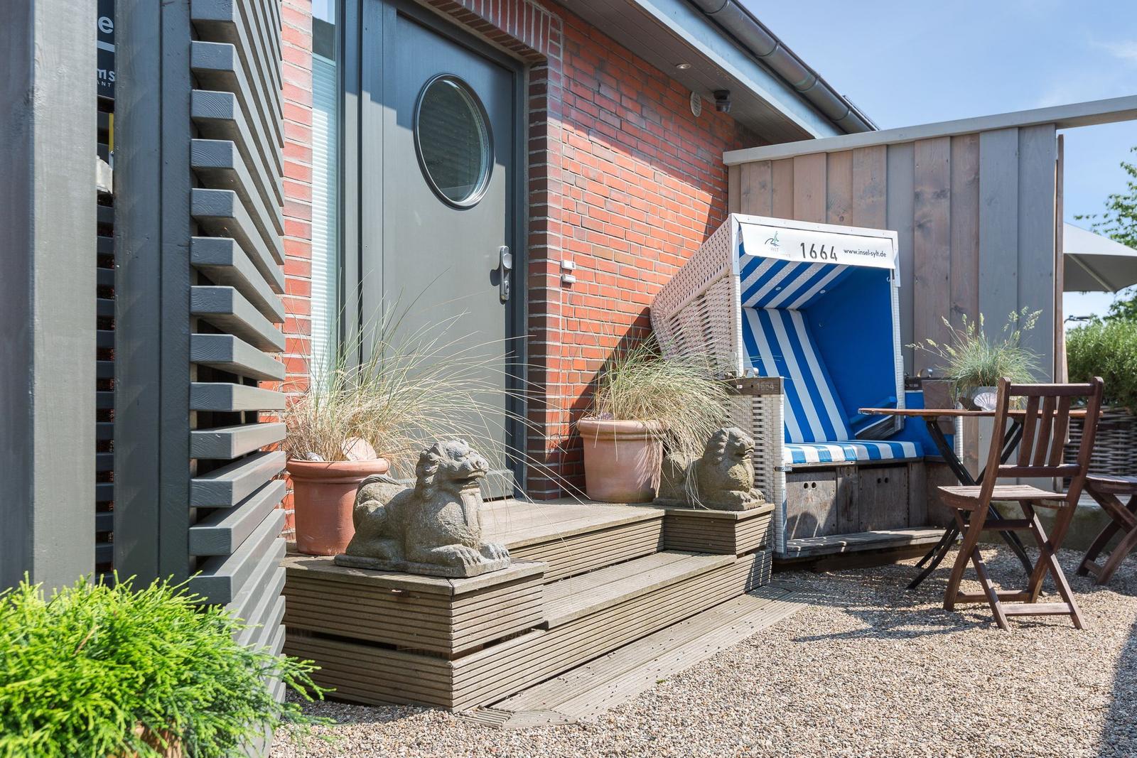 Haus mit Eingangstreppe, Strandkorb und Gartenmöbeln.