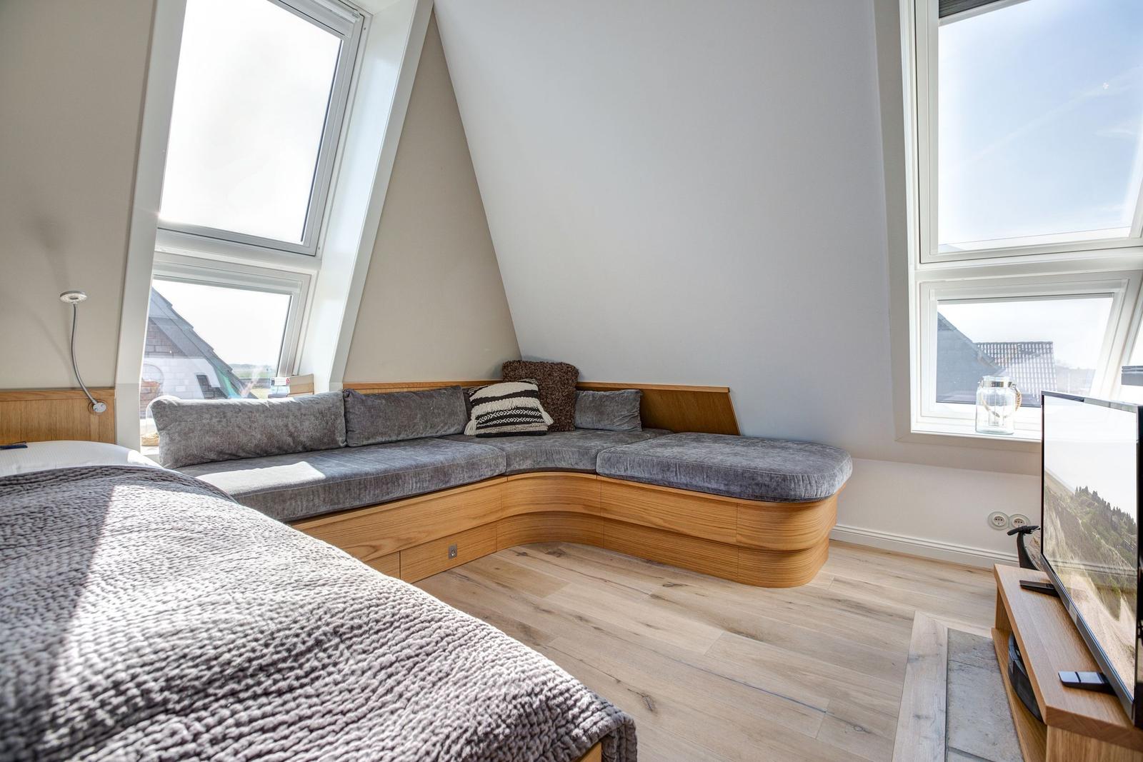 Schlafzimmer mit Bett, Sitzbank und Fenstern
