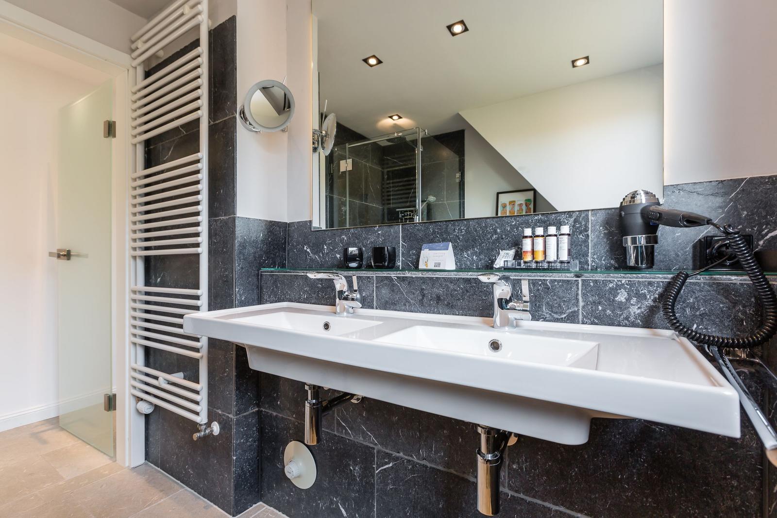 Bathroom with double sink, mirror, and hairdryer.