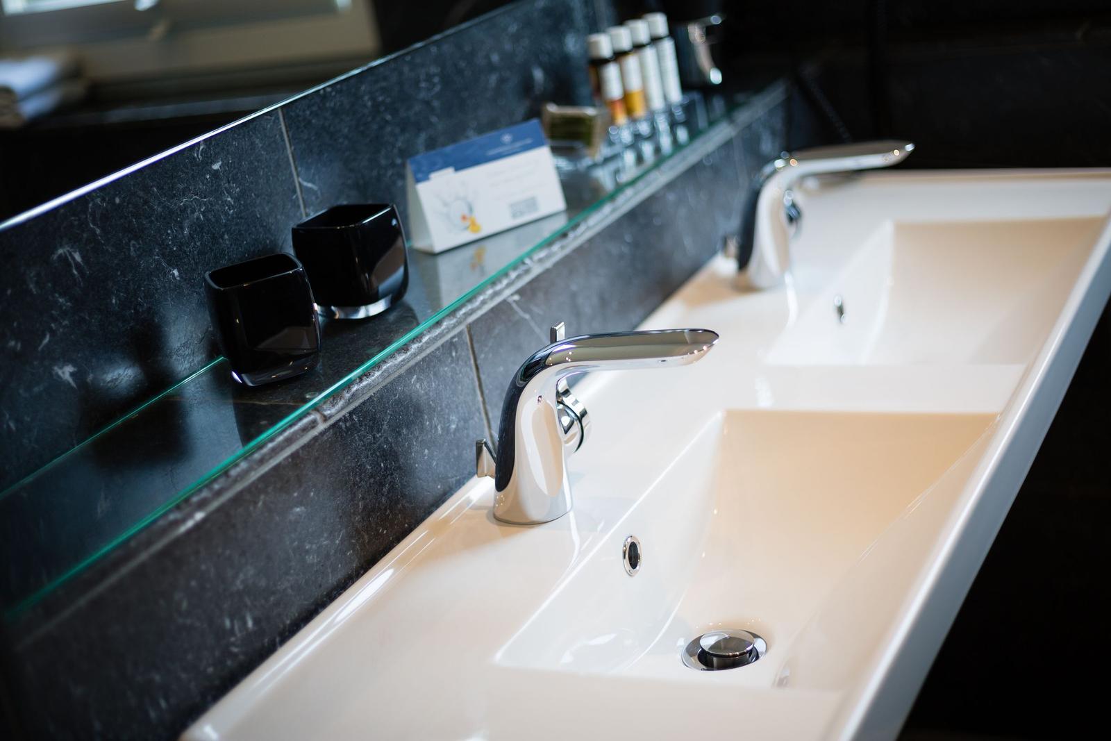Modern double sink with mirror and black ceramic cups.