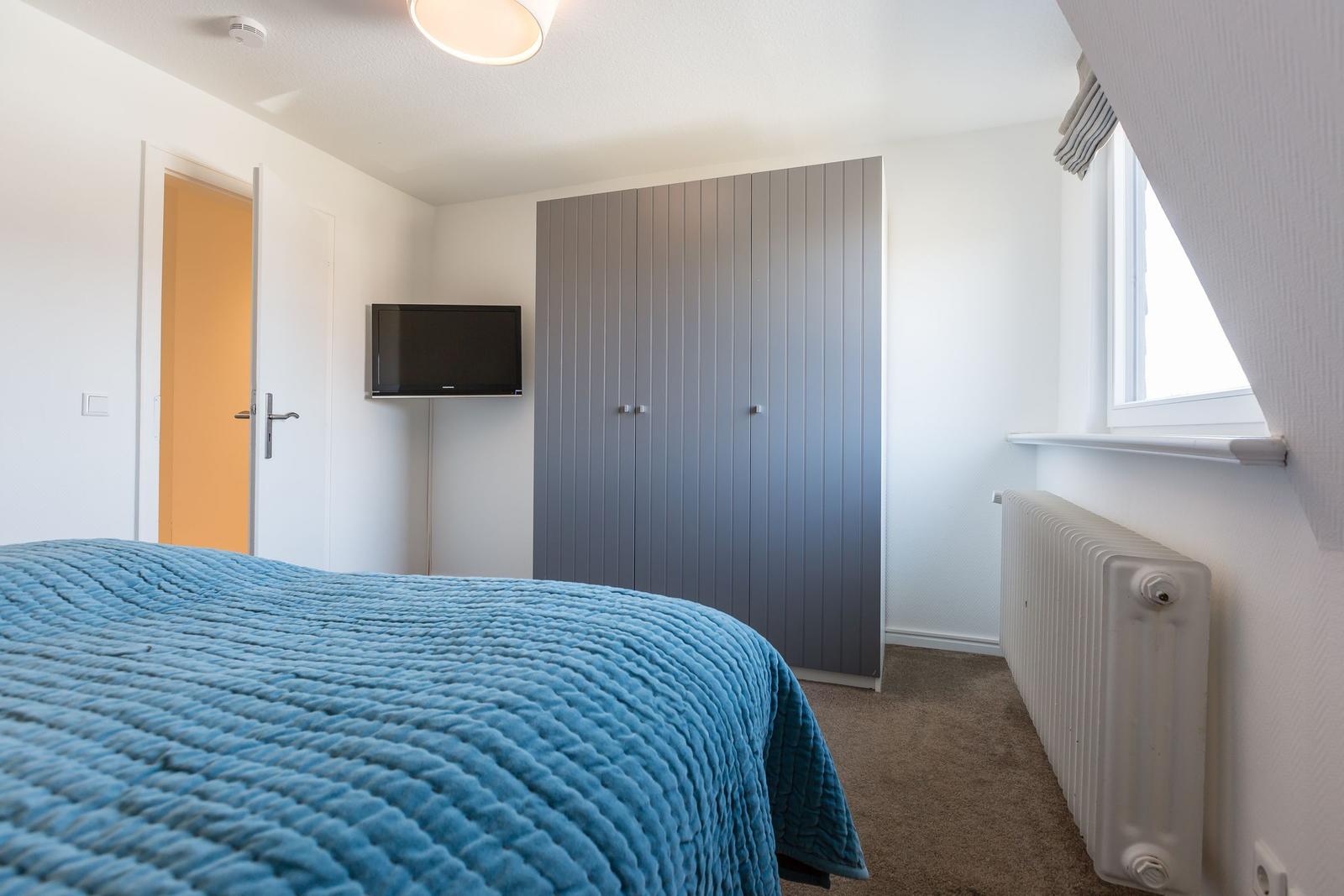 Bedroom with bed, wardrobe, TV, and window.