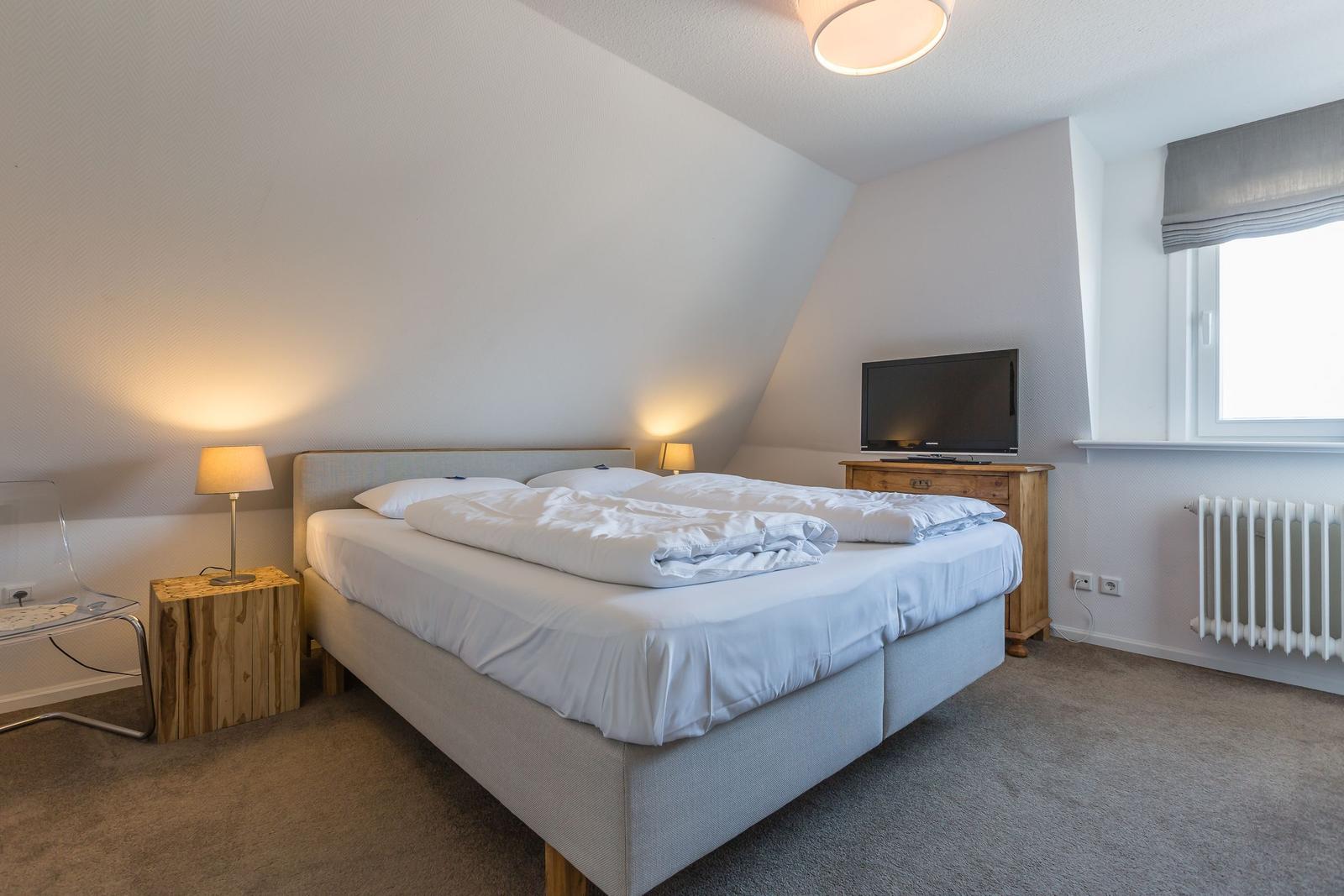 Bedroom with double bed, TV, and window.