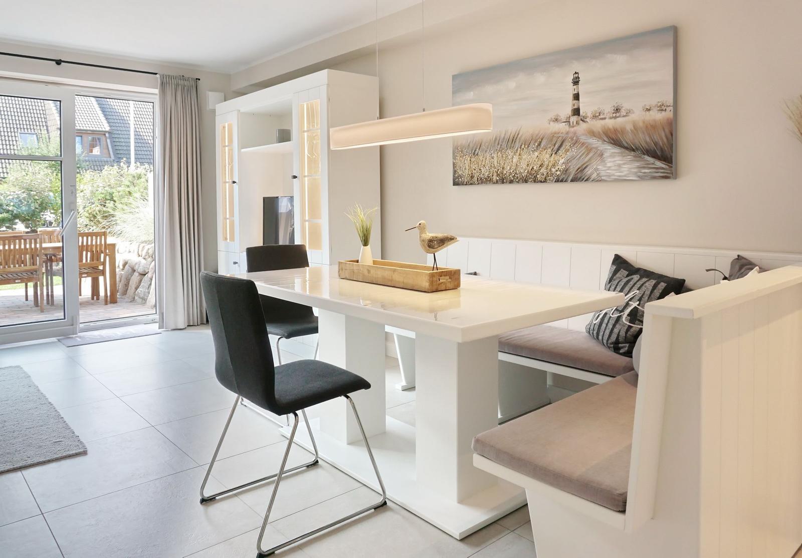 Dining area with white table, bench, and wall art featuring a lighthouse.