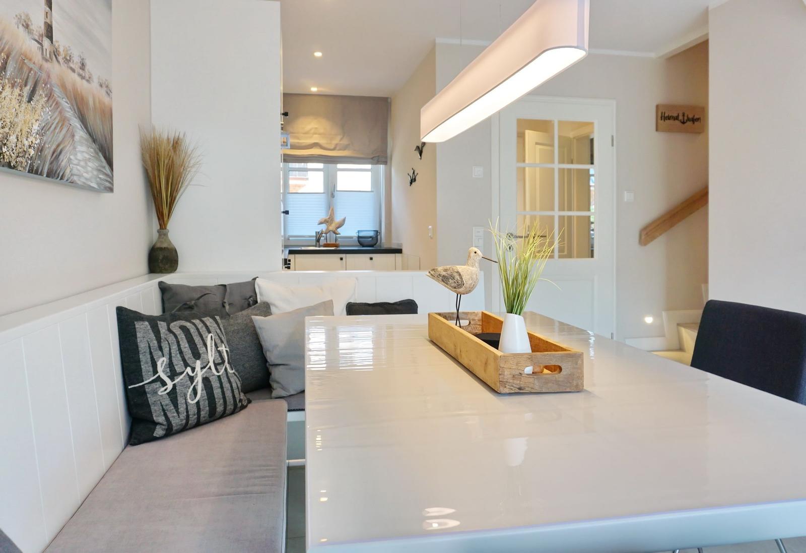 Dining area with white table and bench. Decoration with bird and plant.