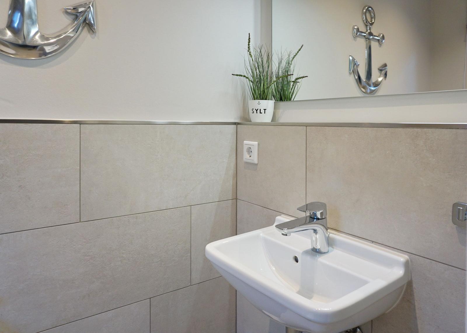 Sink with mirror, plant, and anchor decoration on the wall.