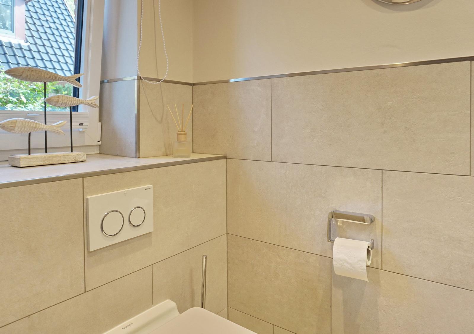 Bathroom with toilet, window, and decorative fish.