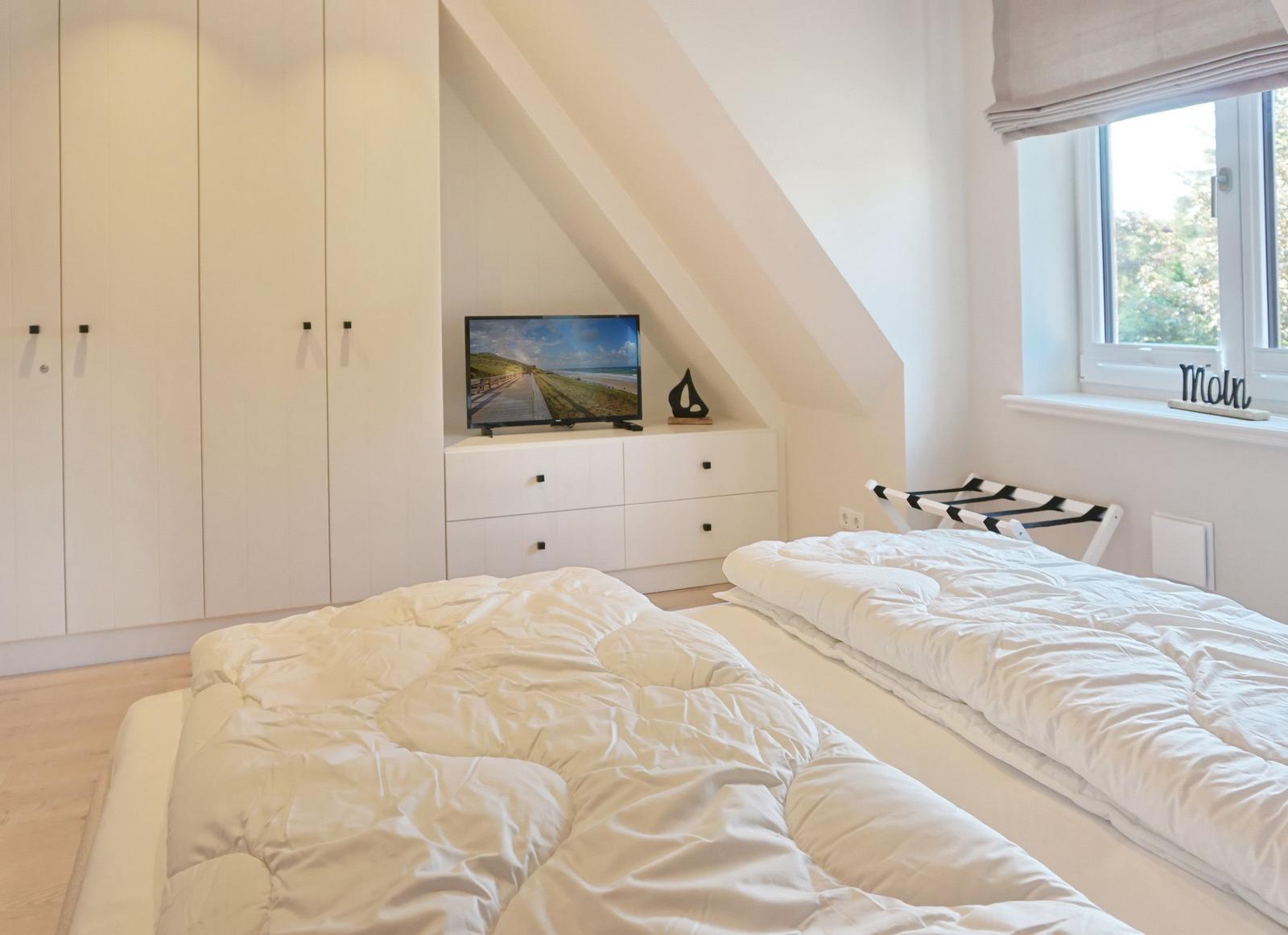 Room with two beds, TV, and window with view.