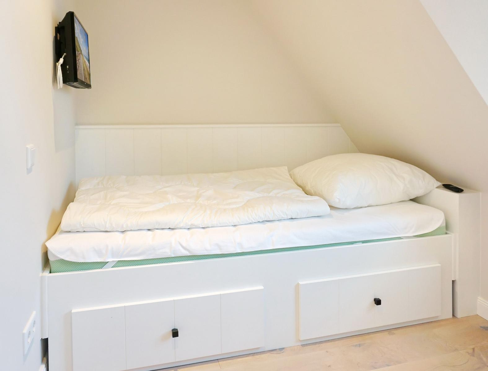 Bedroom with bed, TV, and storage space under the bed.