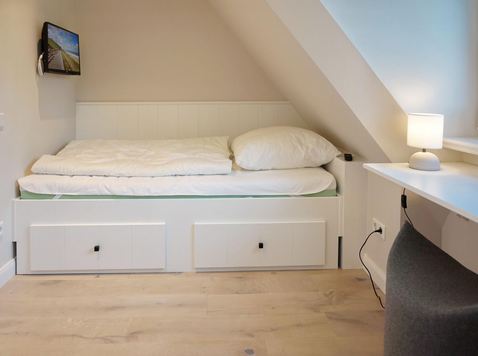 Bedroom with double bed, nightstand, and TV mounted on the wall.