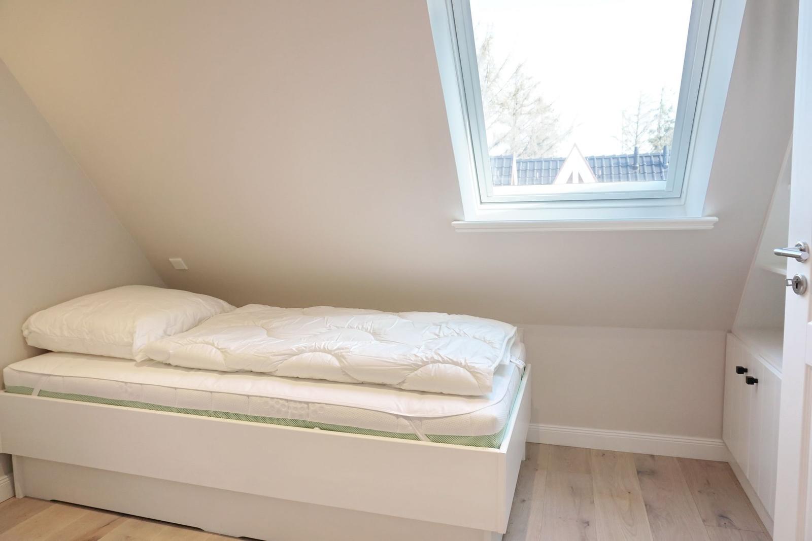 Bedroom with skylight and white bed.