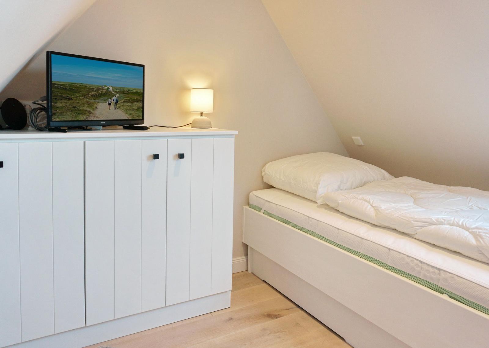 Bedroom with double bed, TV, and bedside lamp.