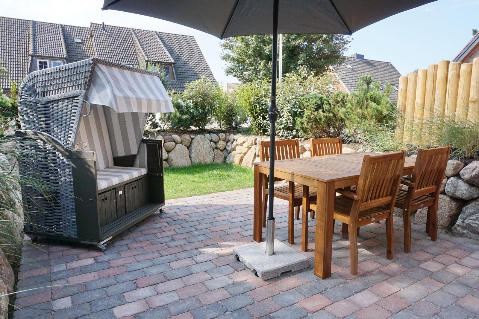 Patio with wooden table, chairs, and umbrella. A beach chair is on the left.