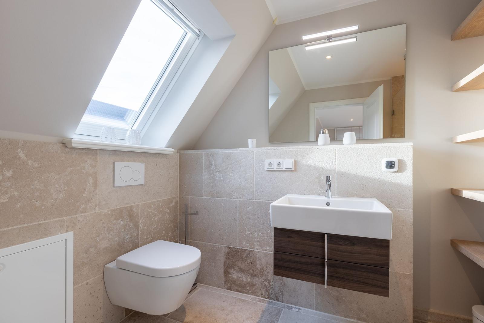 Bathroom with sloped ceiling, sink and toilet under roof