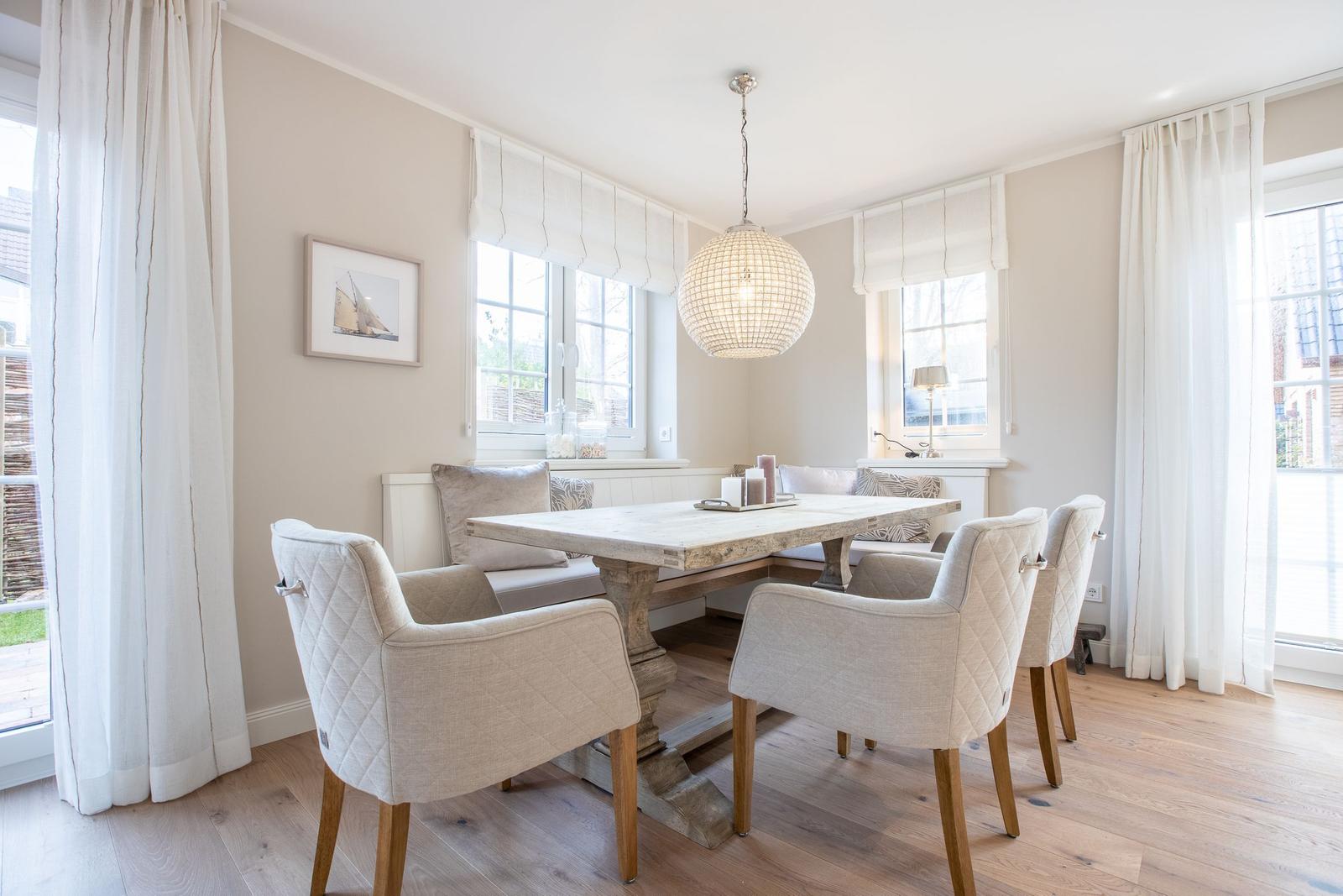 Dining room with table, chairs, and windows. Ceiling light and wooden floor.