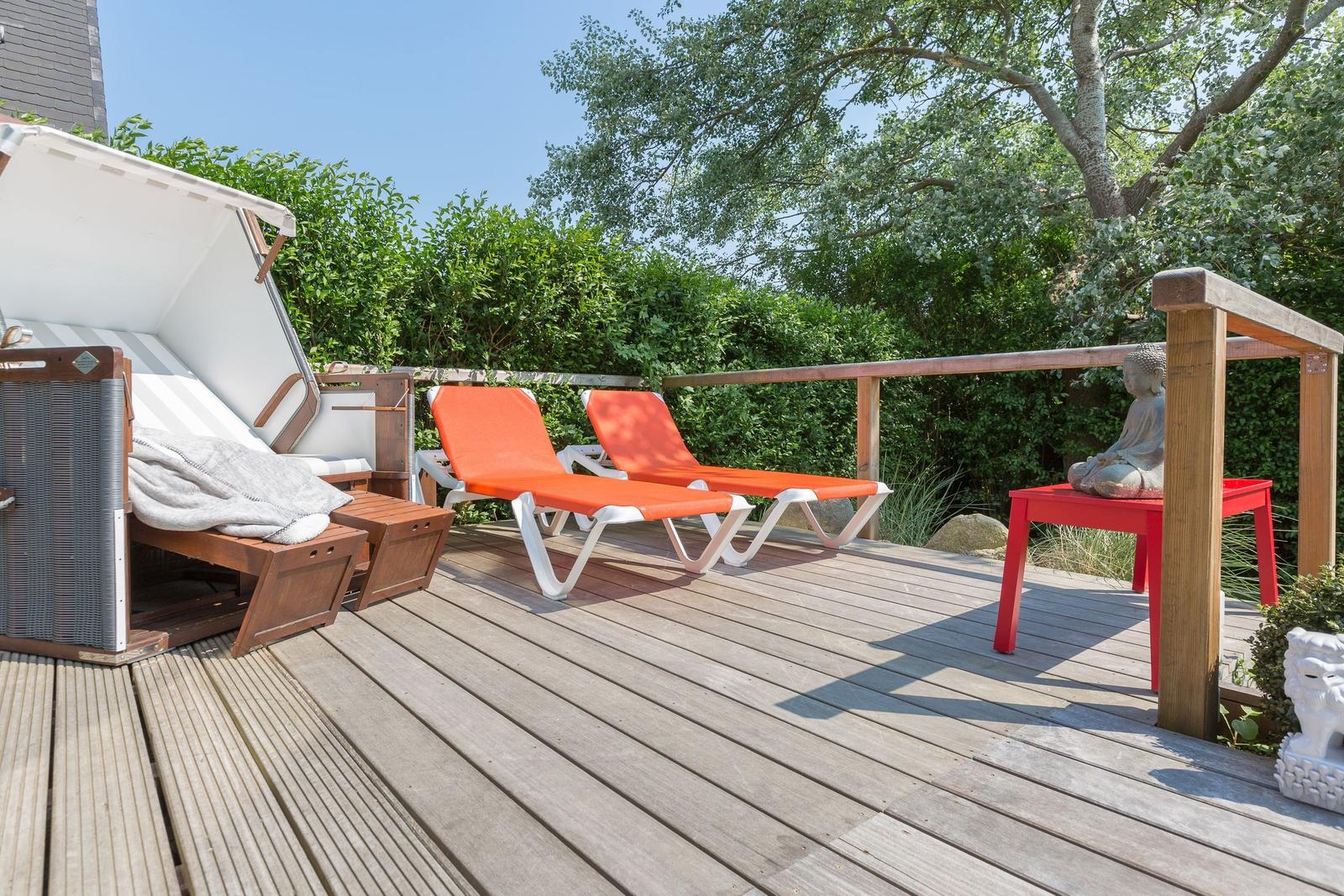 Terrasse mit Liegen, Sonnenschutz und Buddha-Statue.