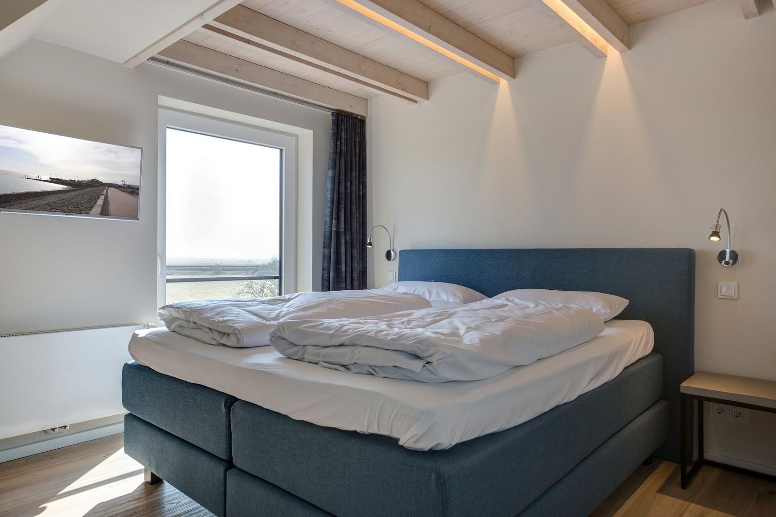 Schlafzimmer mit Doppelbett, Fenster und Holzdecke.