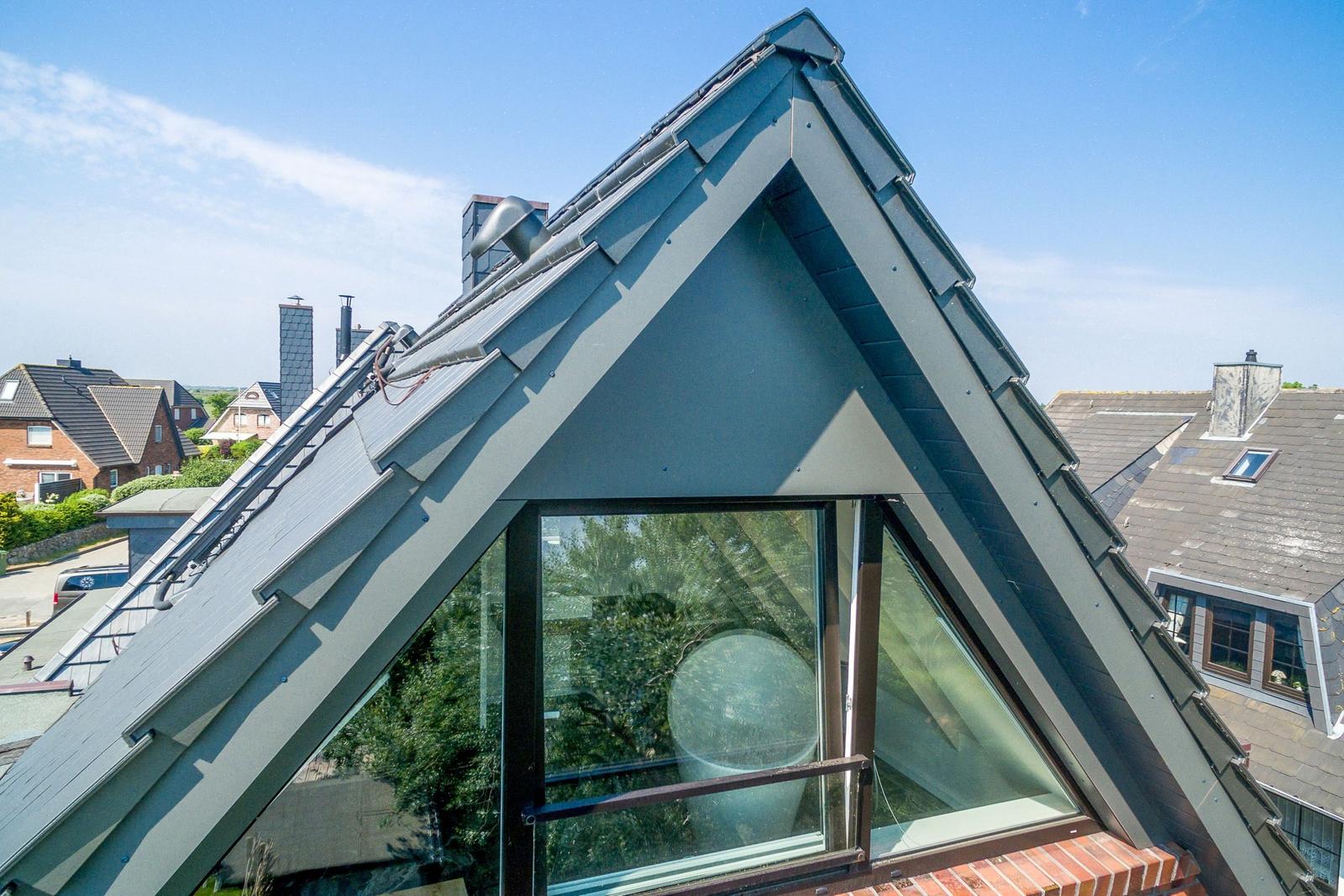 Dachgeschoss mit großem Fenster und Blick auf Nachbarhäuser.