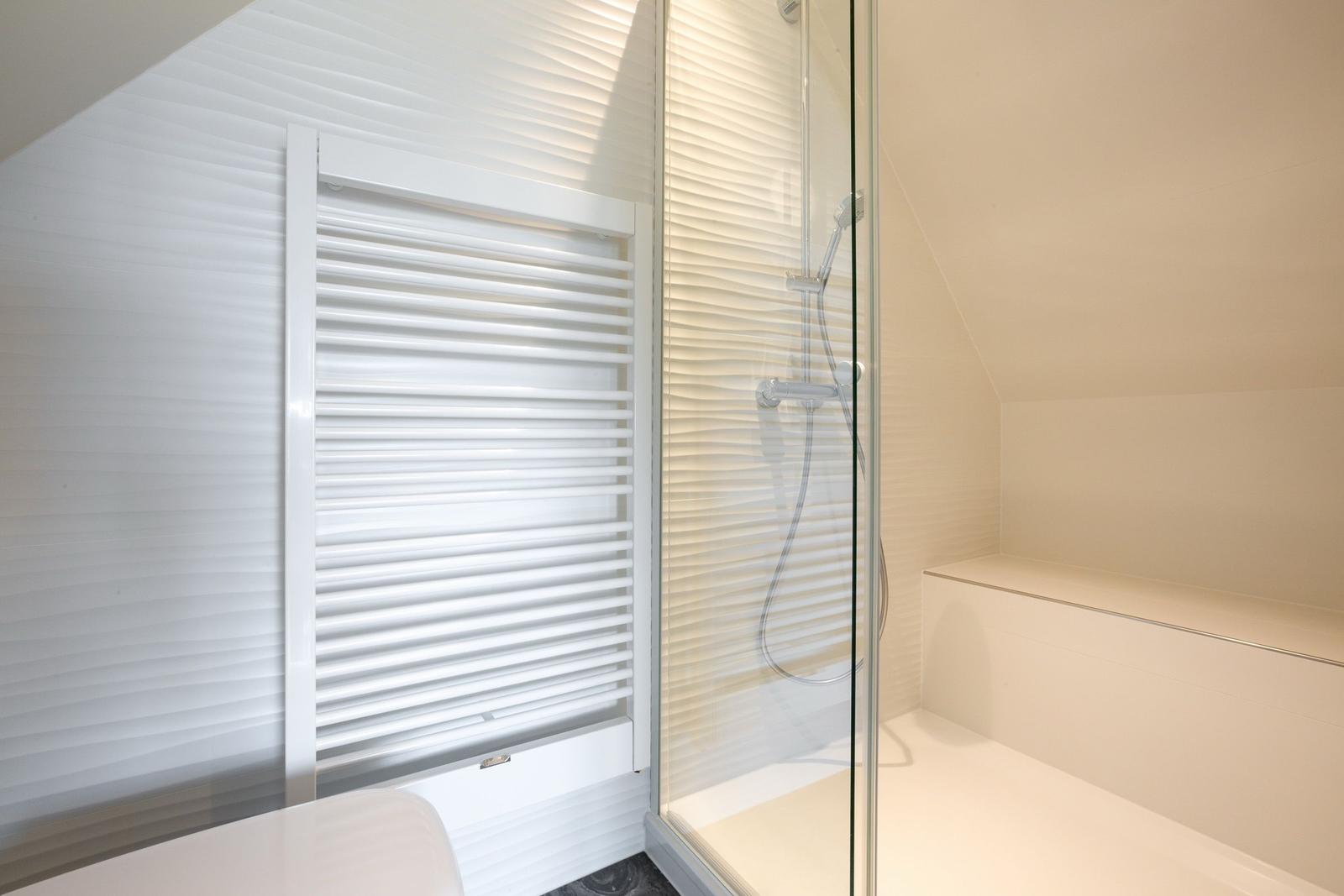 Dusche mit Glaswand und Heizkörper an der Wand