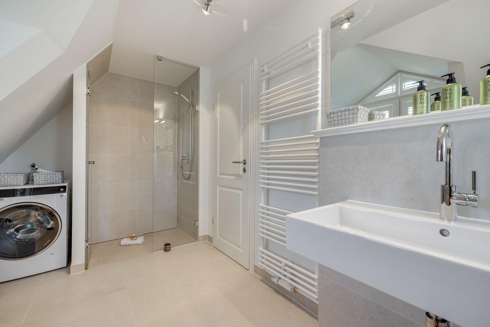 Badezimmer mit Dusche, Waschmaschine und Handtuchwärmer.