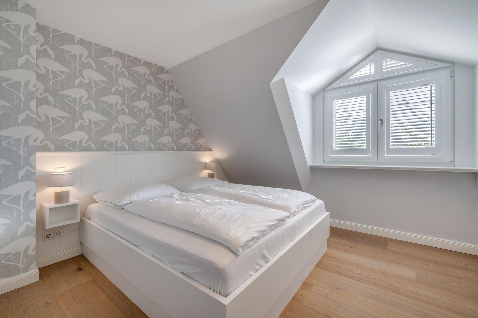 Schlafzimmer mit Dachschrägen, Flamingo-Wand und Doppelschlafplatz.