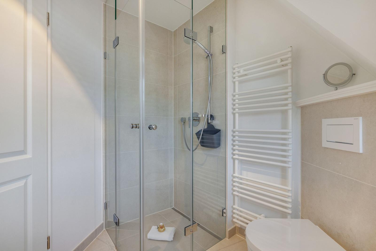 Dusche mit Glaswand, Heizkörper und Toilette