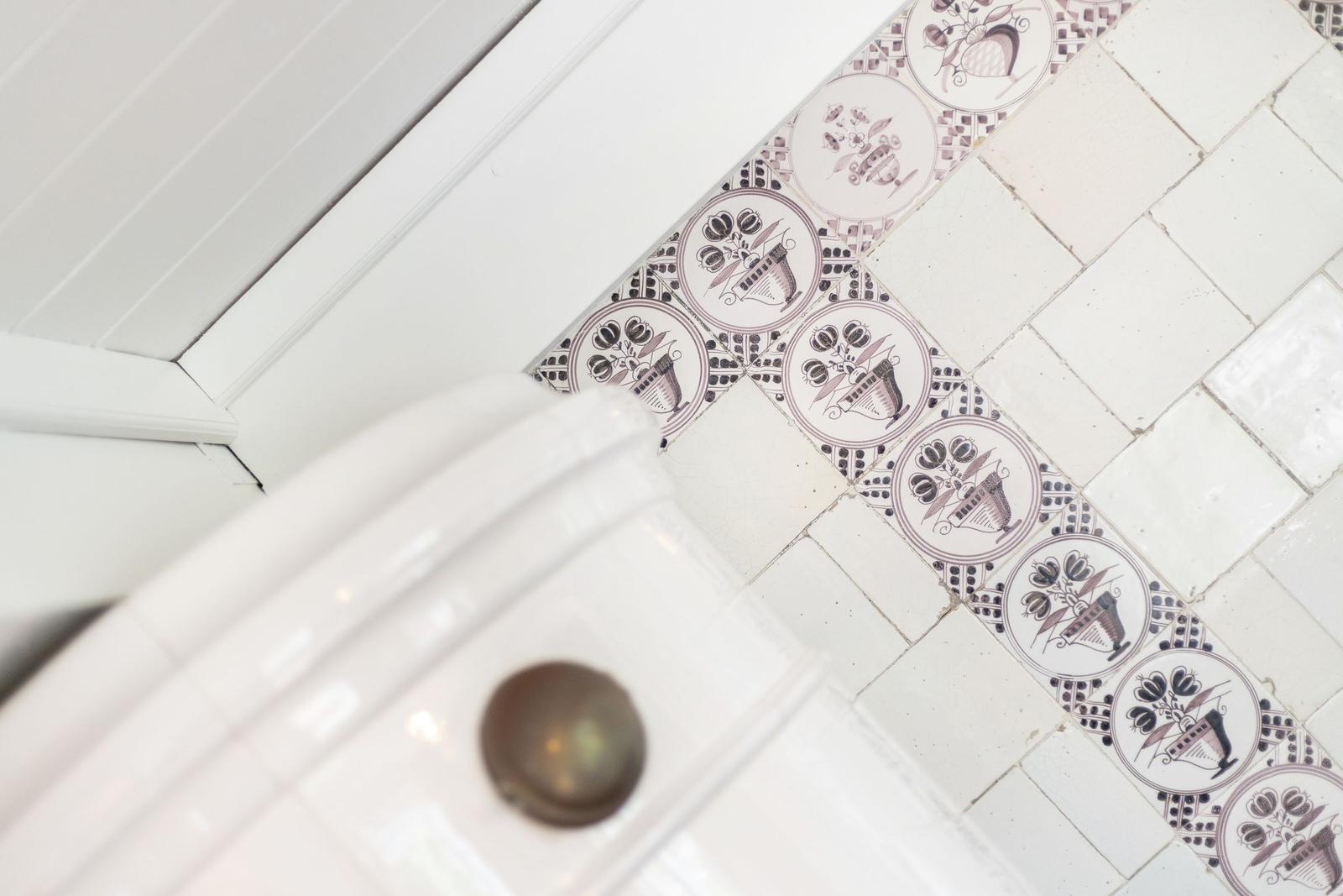 Badezimmer mit dekorativen Fliesen und weißer Wandverkleidung