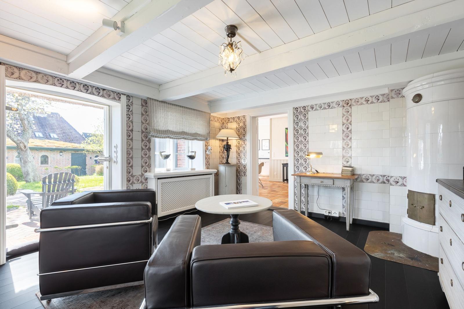 Wohnzimmer mit Ledersofa, Holzboden und Fenster zur Terrasse.