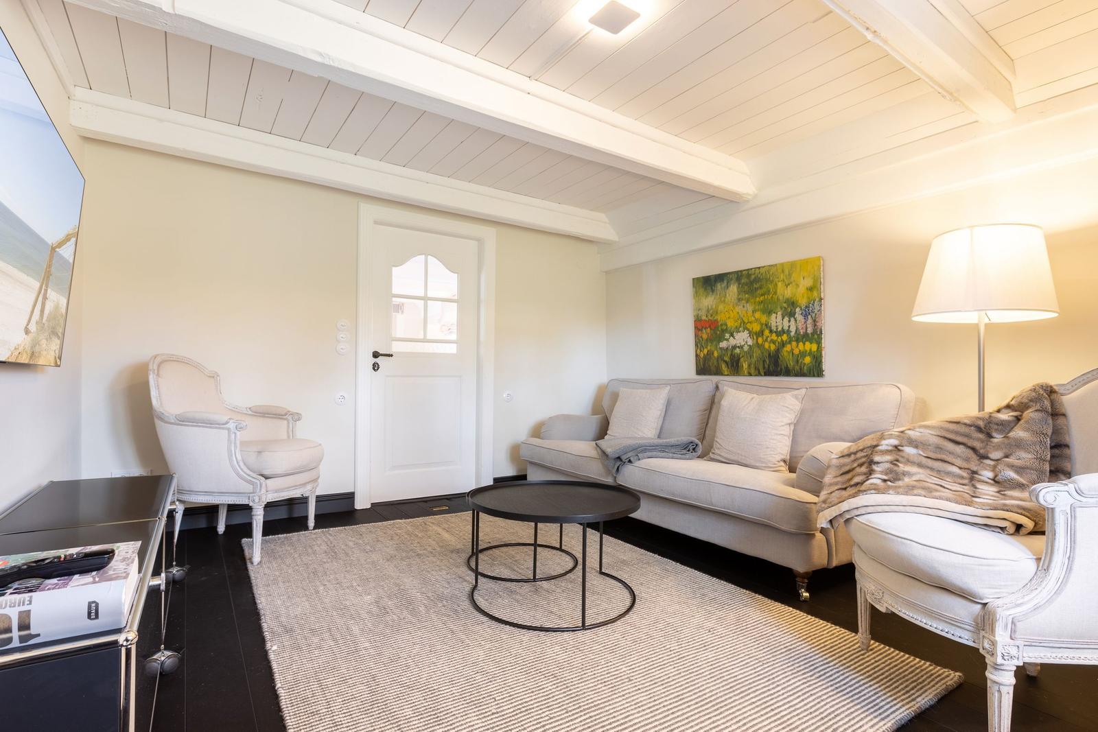Wohnzimmer mit Sofa, Sessel und Tisch auf Teppich