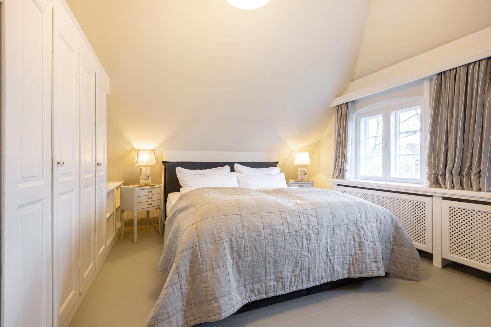 Schlafzimmer mit Bett, Nachttischen und Fenster