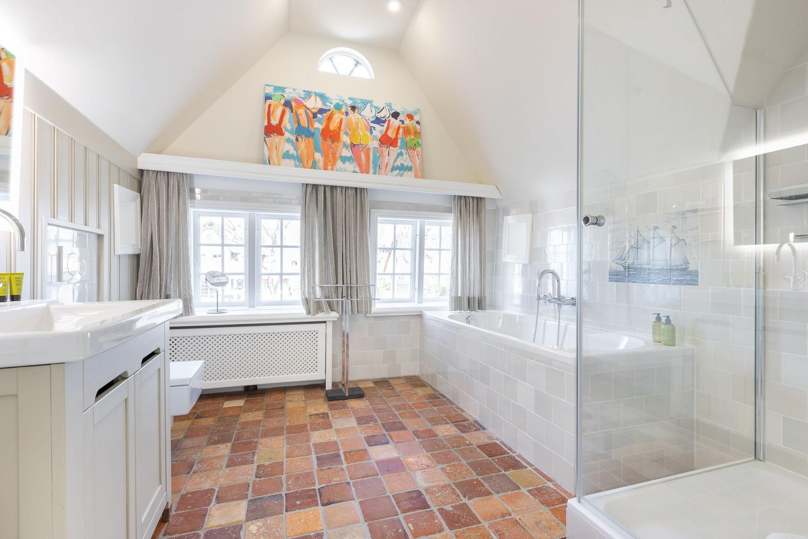 Badezimmer mit Dusche, Badewanne und Terrakottaboden