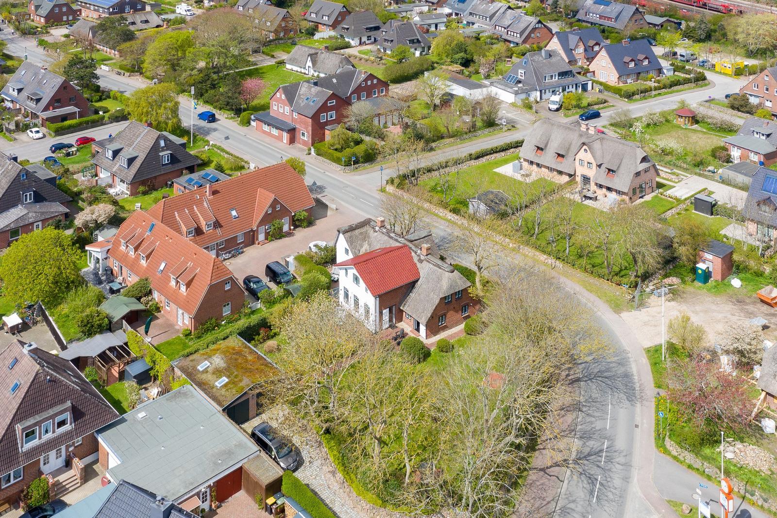 Aerial view of a residential area with houses, roads, and greenery.