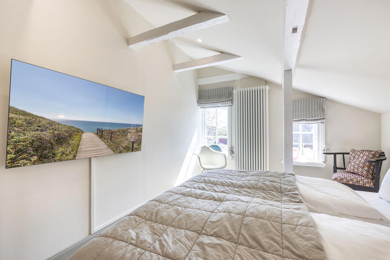 Schlafzimmer mit Dachschrägen, Bett, Fenster und Wandbild