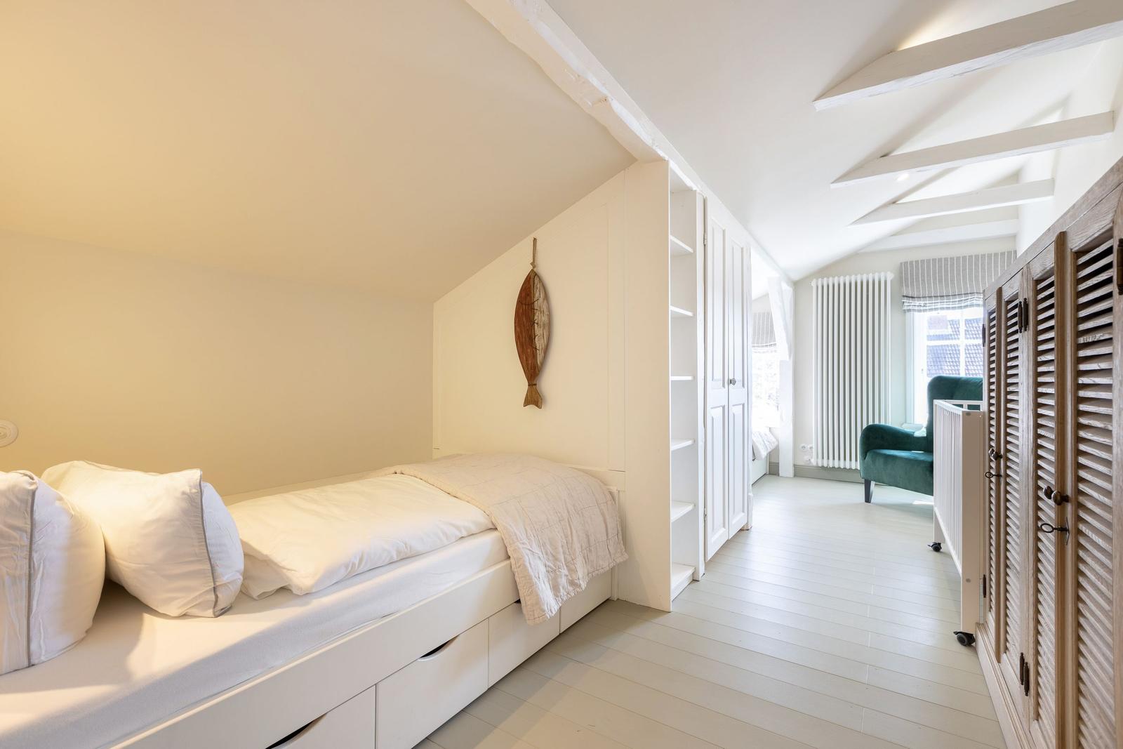 Schlafzimmer mit Bett, Kleiderschrank und Sitzgelegenheit
