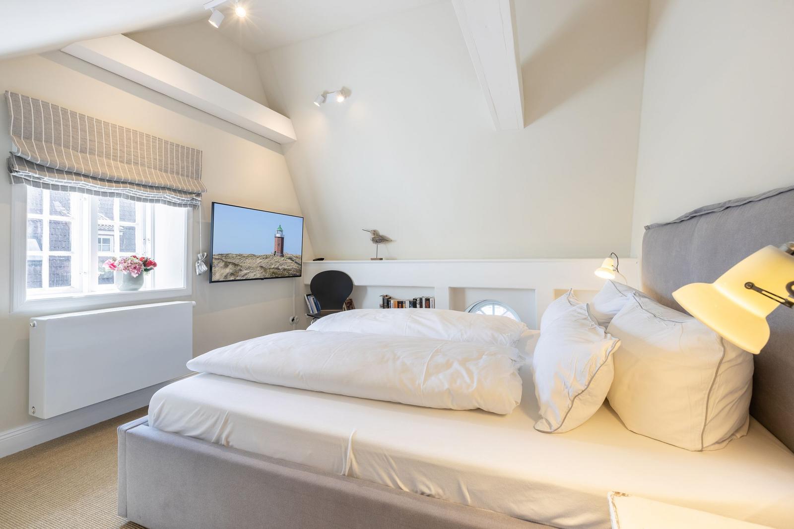 Bedroom with double bed, window, TV, and lamp.