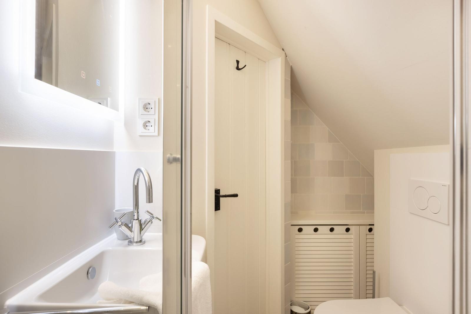 Bathroom with shower, sink, and toilet under sloped ceiling