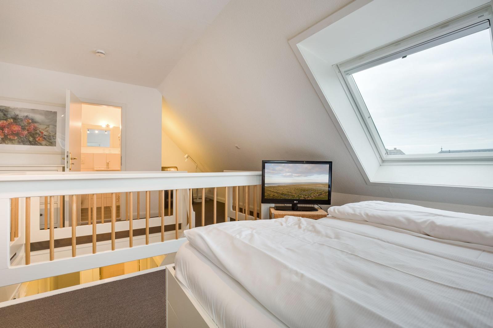 Bedroom with skylight, bed, and TV. View into adjacent room.