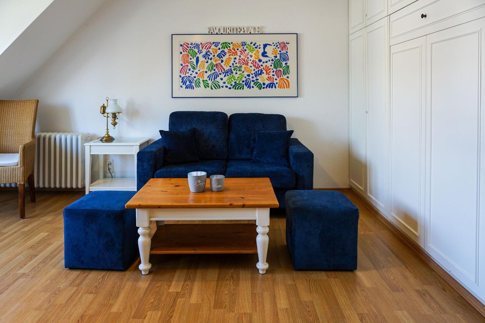 A living room with blue sofa, wooden table, and wall art.